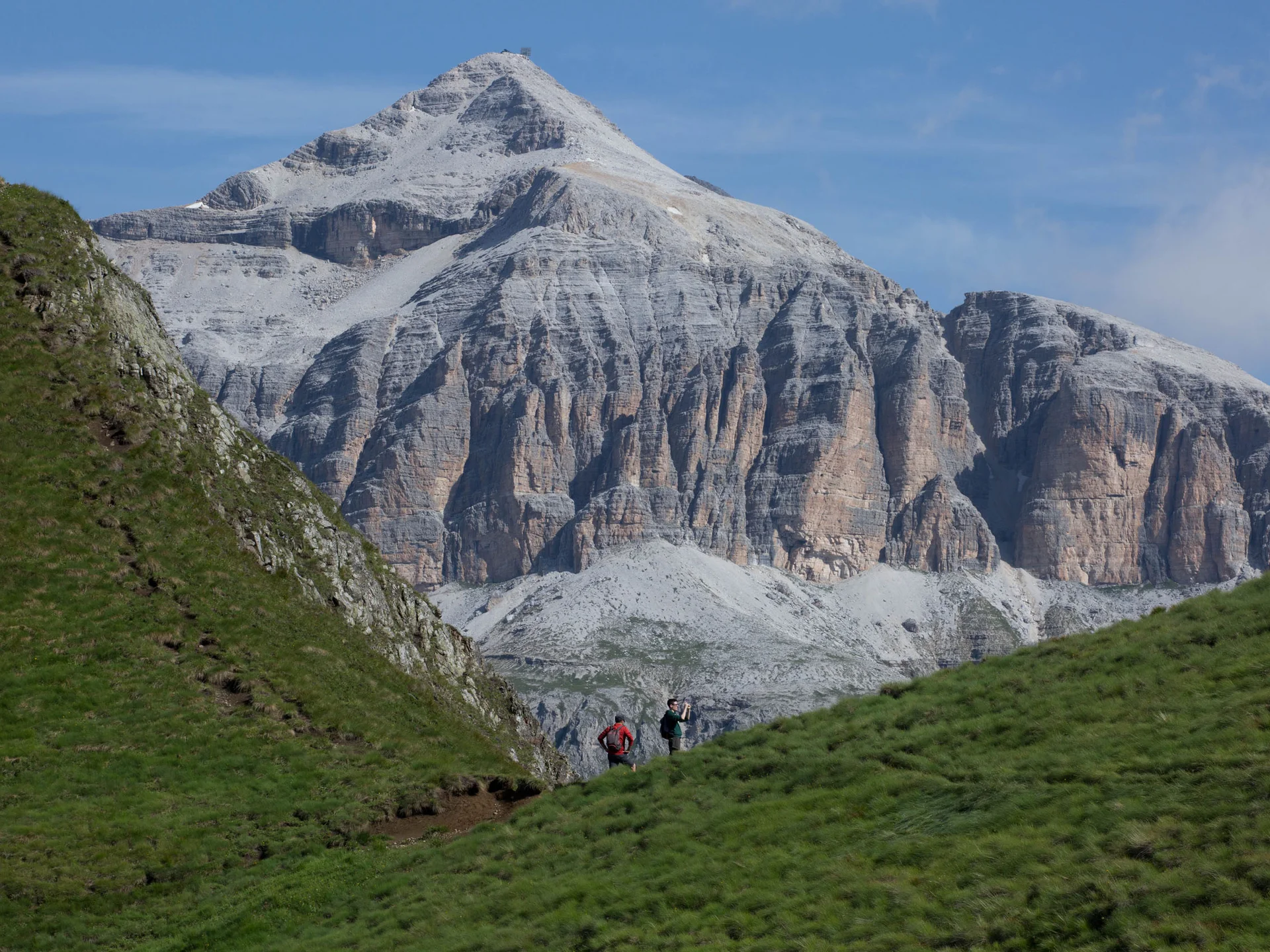 Il tuo Chalet ad Arabba: Chalet Barbara, charme alpino. Montagna rocciosa con due escursionisti su un sentiero verde