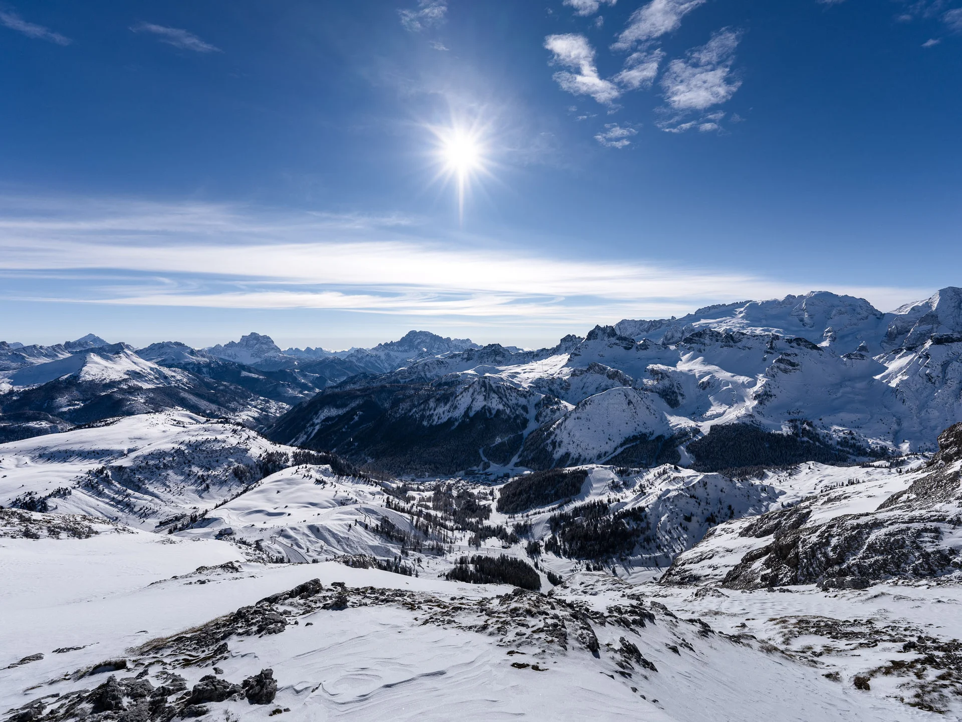 Il tuo Chalet ad Arabba: Chalet Barbara, charme alpino. Panorama montano innevato con sole splendente e cielo parzialmente nuvoloso