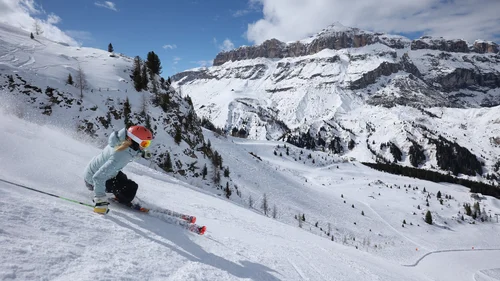Il tuo Chalet ad Arabba: Chalet Barbara, charme alpino. Sciatore con casco rosso su pista innevata con montagne sullo sfondo