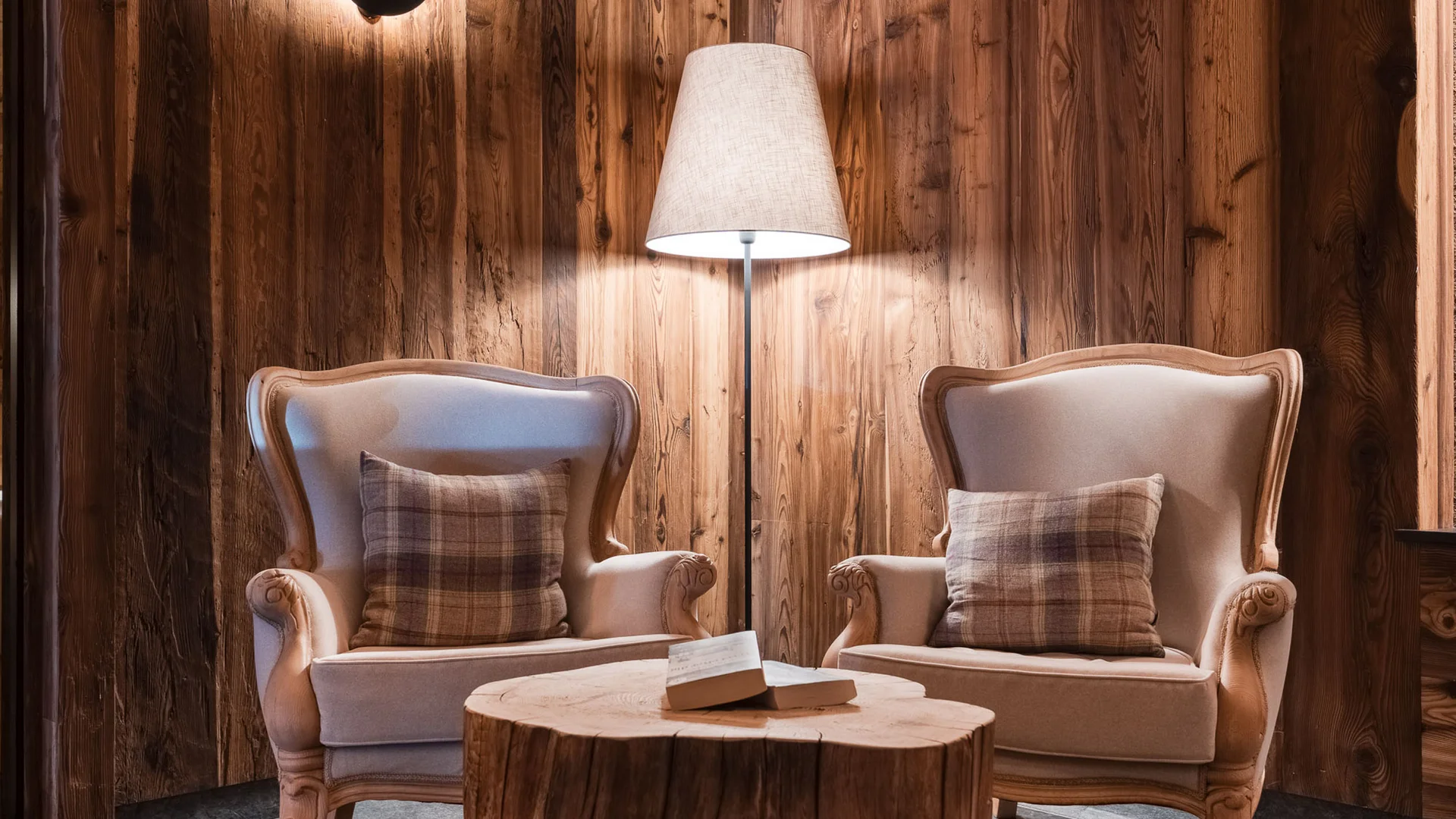 Il tuo Chalet ad Arabba: Chalet Barbara, charme alpino. Due poltrone beige con cuscini a quadri e tavolino in legno in un ambiente rustico