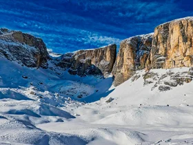 Il tuo Chalet ad Arabba: Chalet Barbara, charme alpino. Montagne rocciose innevate sotto un cielo blu con nuvole sparse