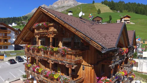 Il tuo Chalet ad Arabba: Chalet Barbara, charme alpino. Casa di legno con balconi fioriti in montagna soleggiata