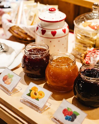 Il tuo Chalet ad Arabba: Chalet Barbara, charme alpino. Barattoli di marmellata assortita con etichette e posate su tavolo di legno