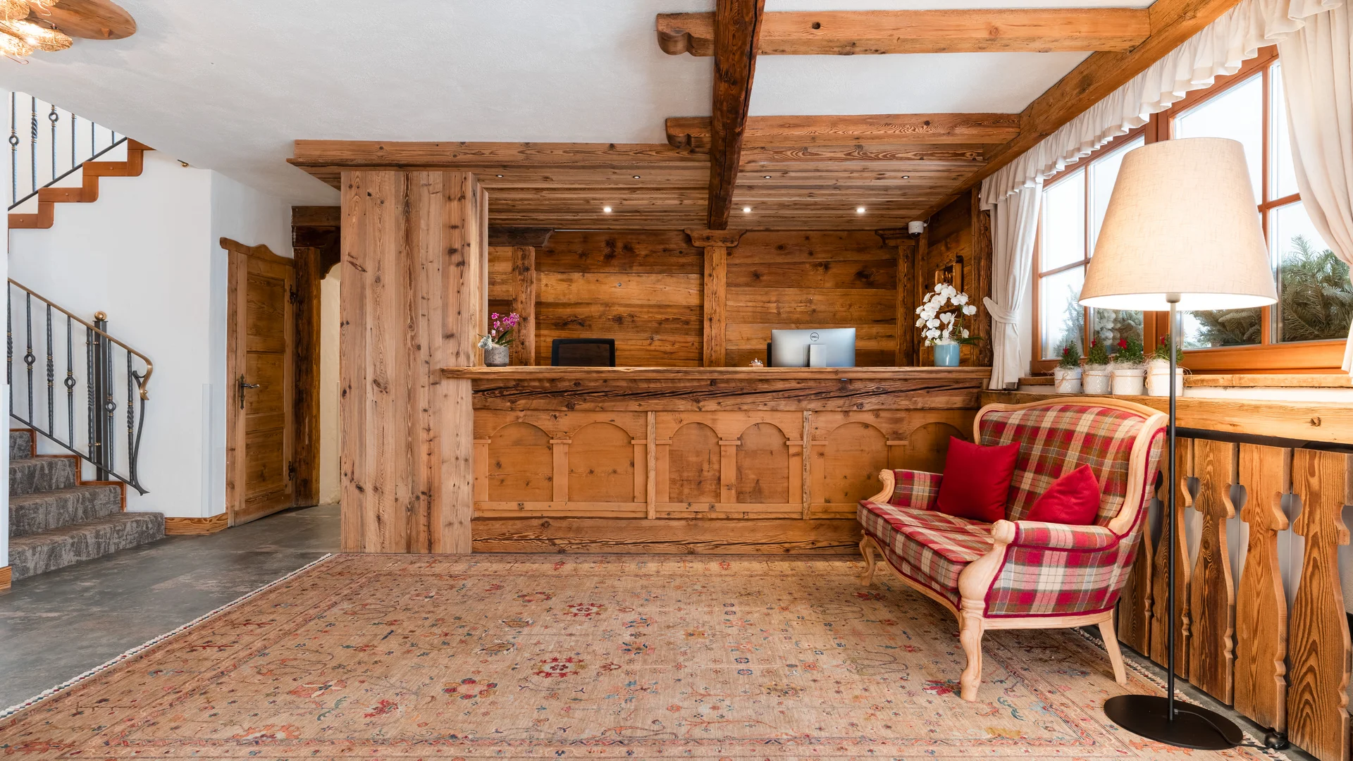 Il tuo Chalet ad Arabba: Chalet Barbara, charme alpino. Reception in legno rustico con divano a quadri e lampada da terra