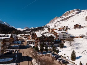 Il tuo Chalet ad Arabba: Chalet Barbara, charme alpino. Paesino di montagna innevato con case in legno e strada soleggiata
