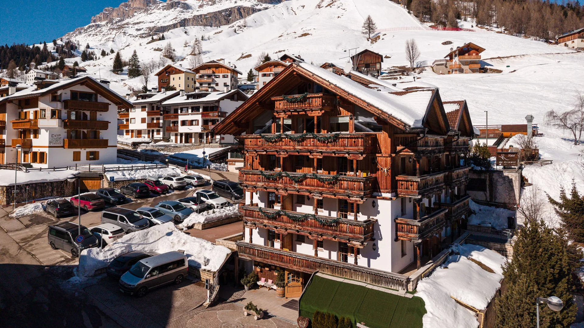 Il tuo Chalet ad Arabba: Chalet Barbara, charme alpino. Hotel in legno con balconi fioriti e montagne innevate sullo sfondo