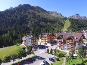 Il tuo Chalet ad Arabba: Chalet Barbara, charme alpino. Piccolo villaggio alpino con case tradizionali e montagne verdi sullo sfondo